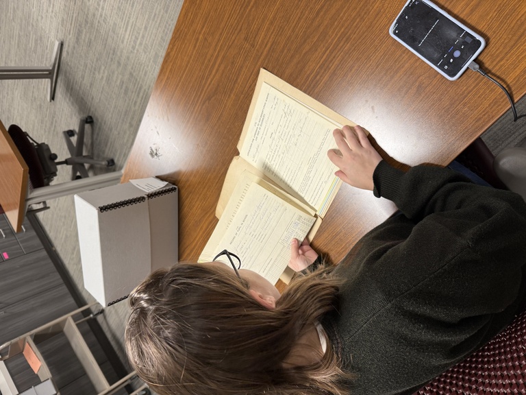 A person sitting at a desk scanning Indian Boarding School Records